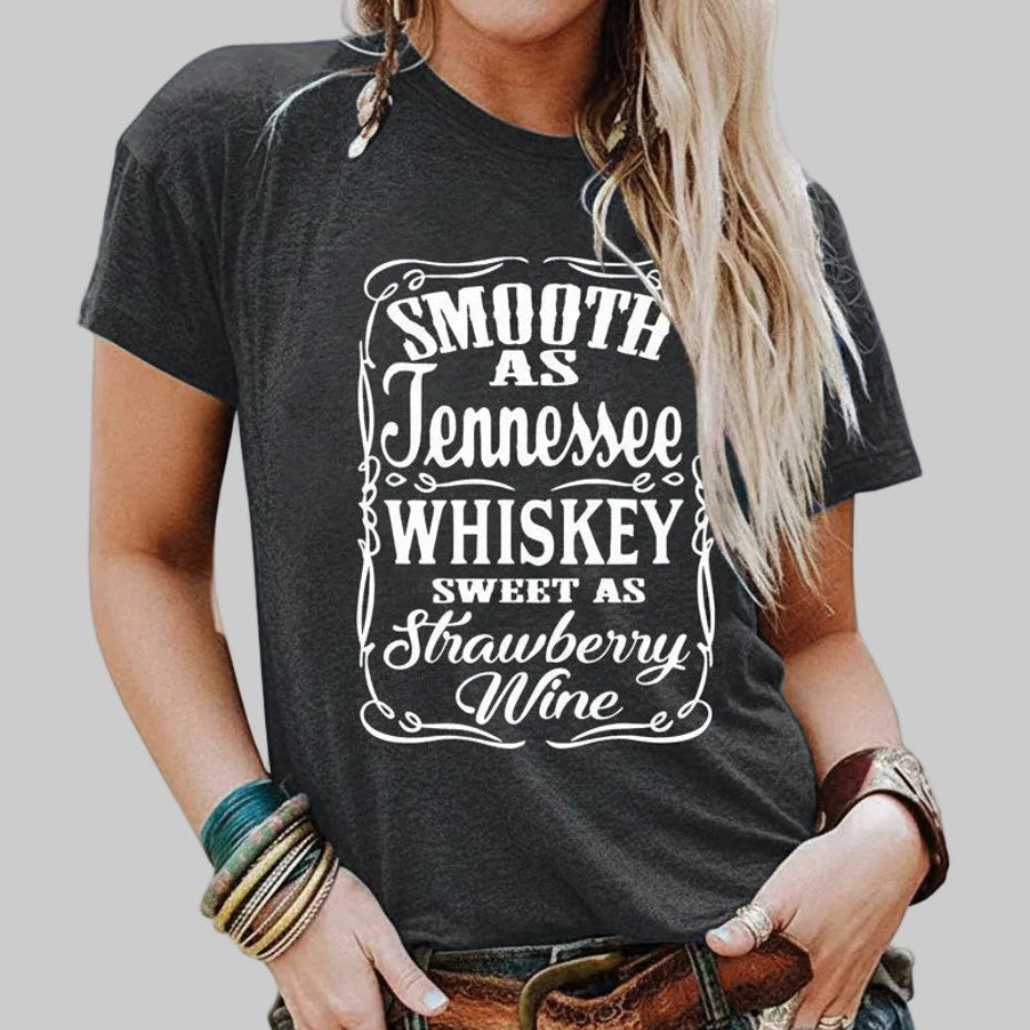 Dark gray short-sleeve crew neck graphic tee reading "Smooth as Tennessee Whiskey Sweet as Strawberry Wine," styled with denim shorts and a western belt | The Pretty Pistol