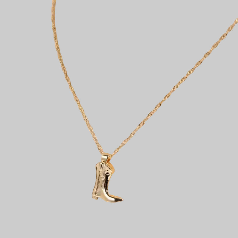 Western boot charm pendant necklace in bright gold finish on a twisted chain, displayed on a clear acrylic stand | The Pretty Pistol