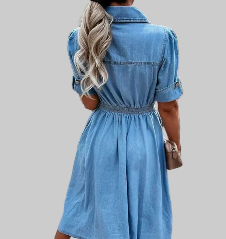 Light blue button-front denim shirt dress with pointed collar, elasticated waist, dual chest flap pockets, and flowy gathered A-line midi skirt | The Pretty Pistol