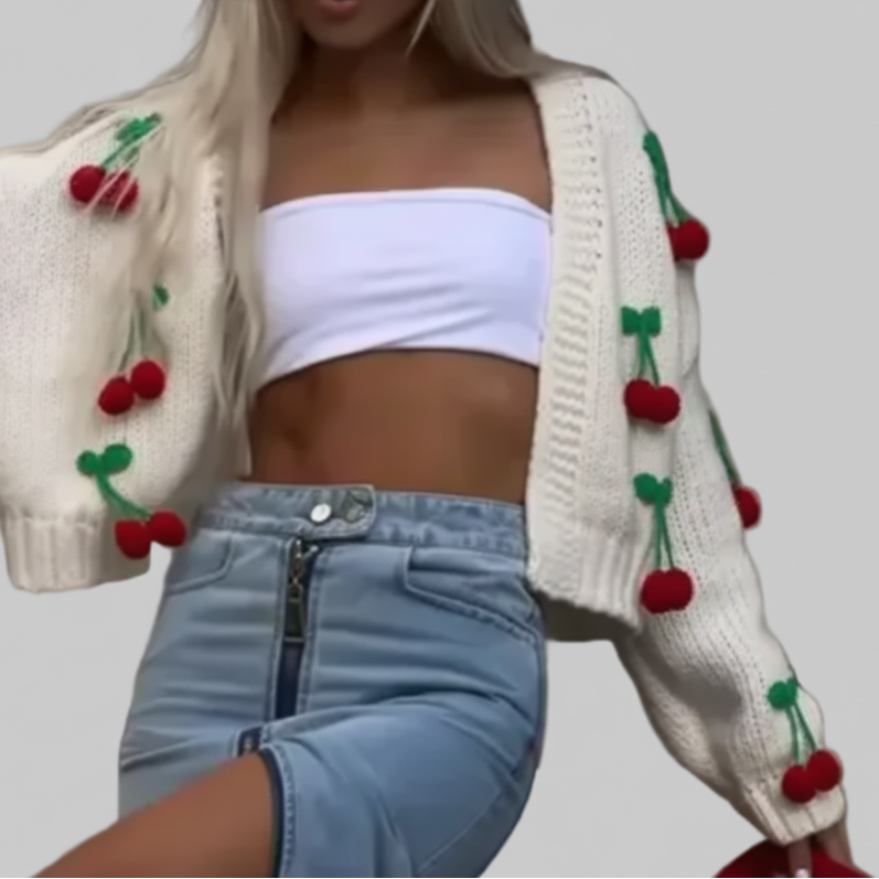 Close-up of cream cherry knit cardigan with balloon sleeves and 3D red cherry appliqués, worn open over a white bandeau crop top and denim mini skirt | The Pretty Pistol