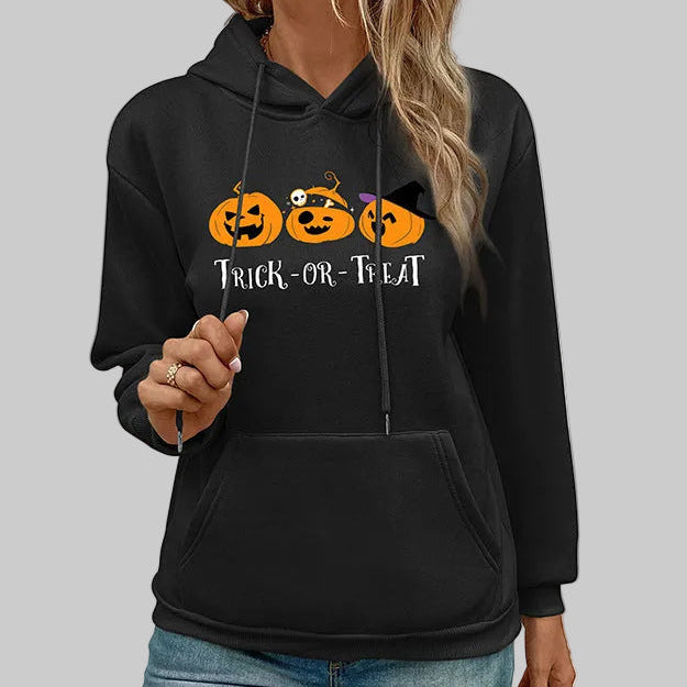 Black Halloween pullover hoodie with Trick-or-Treat jack-o-lantern graphic and kangaroo pocket, styled with jeans, gray background | The Pretty Pistol